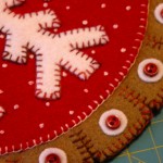 Close up of variegated red thread, french knots and tabbed backing